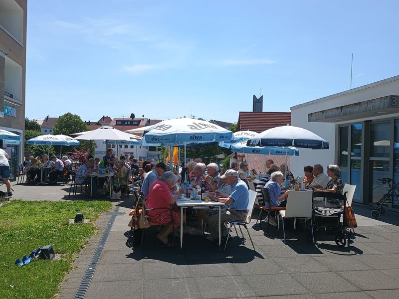 Open-Air-Mittagstisch vor Bürger-Café mit Gästen unter Sonnenschirmen