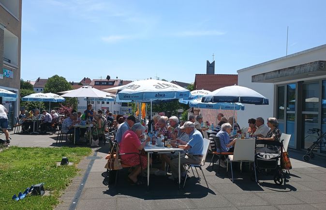 Open-Air-Mittagstisch vor Bürger-Café mit Gästen unter Sonnenschirmen