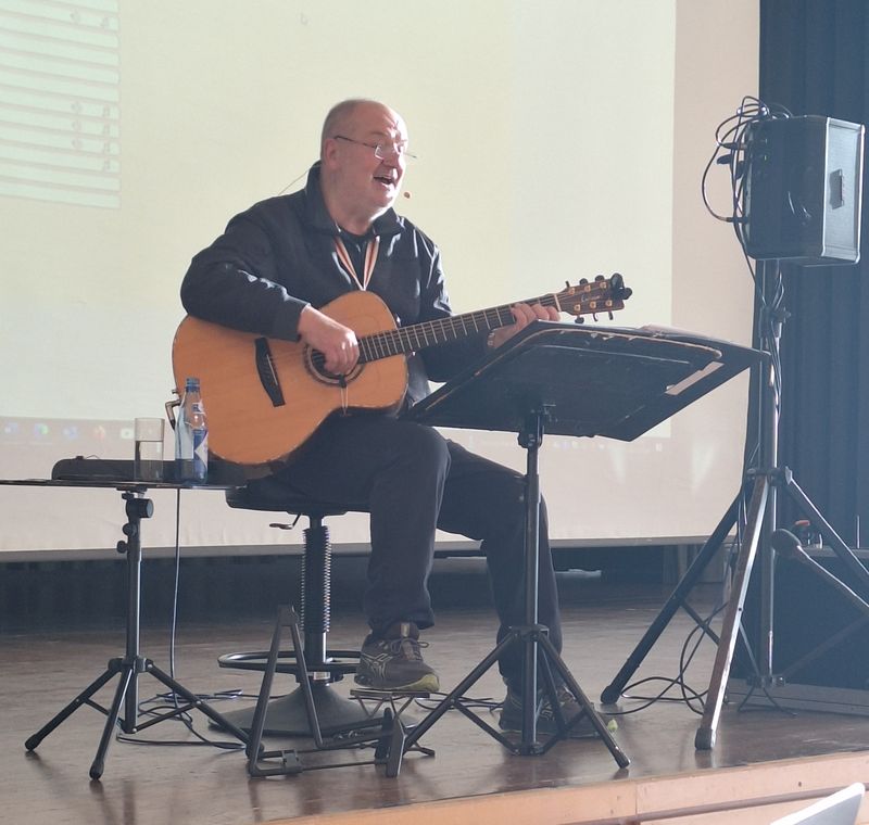 Musiker singt und spielt Gitarre bei Bühnenauftritt neben Lautsprecher